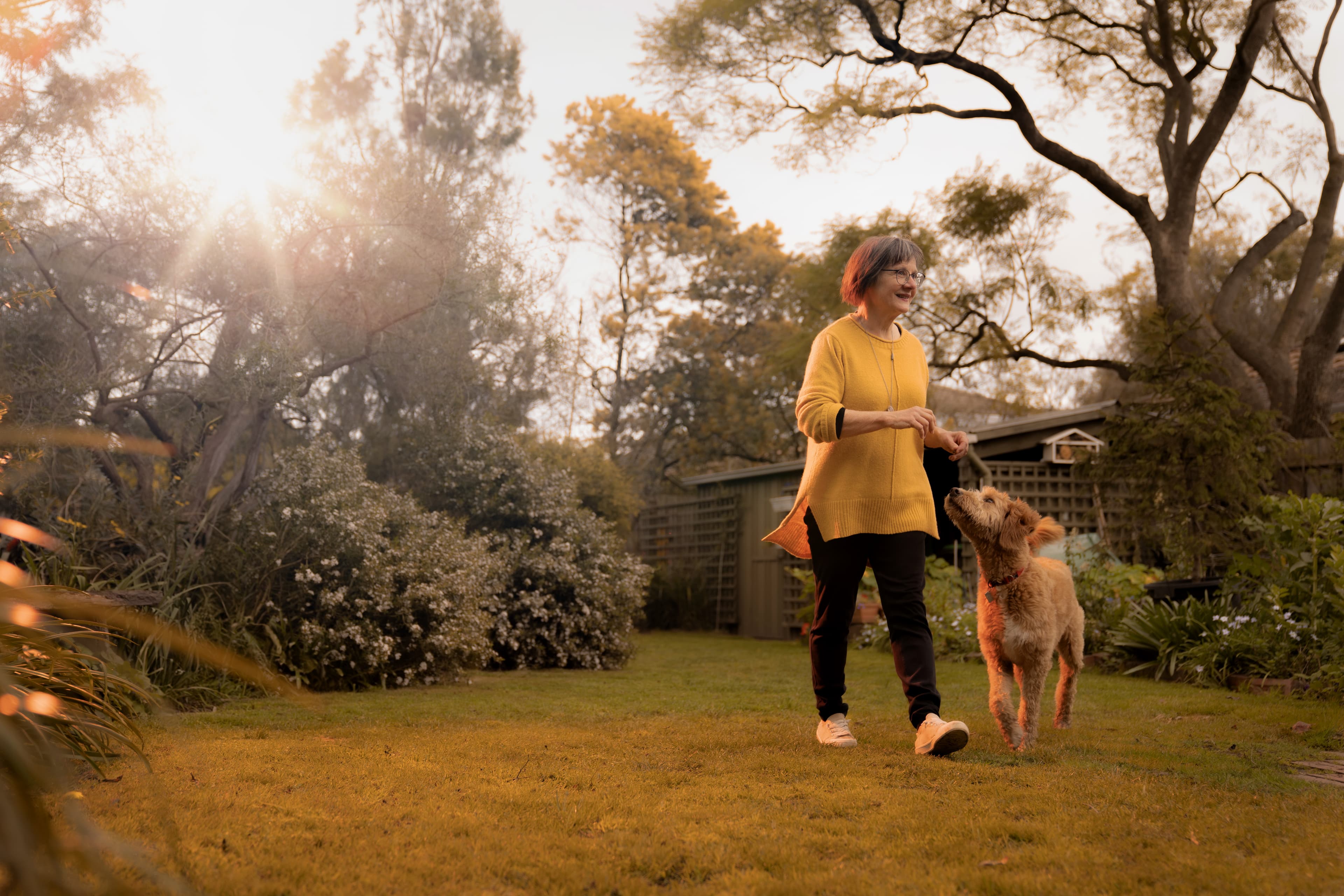 Woman wearing Umps personal alarm pendant, laughing with family over coffee