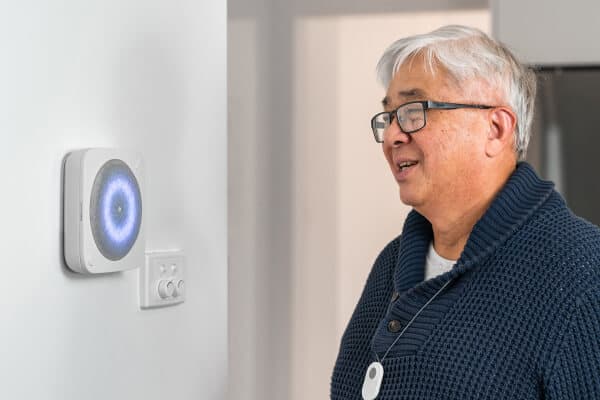 Resident wearing Umps pendant alarm next to wall-mounted Hub